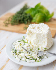 Ricotta cheese mixed with herbs lies on a white plate.