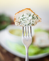 Ricotta cheese mixed with herbs in a chicken roll on a fork.