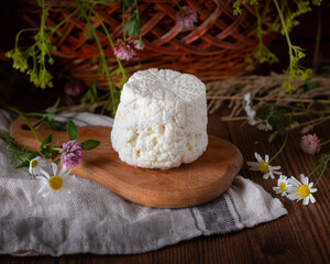 Ricotta cheese lies on a wooden board with wildflowers.