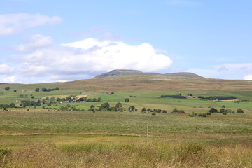 The famous peak of Ingleborough in the Yorkshire Dales National Park surrounded by lush grassland.