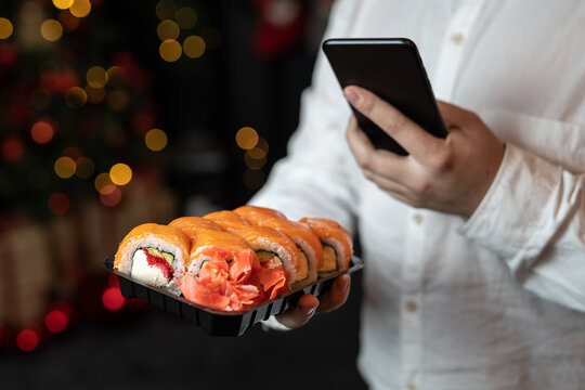 The guy takes a picture on the phone of the delivery of Japanese rolls with salmon