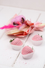 Pink Chocolate dipped Strawberries and Pink Dried Flowers Bouquet, on white wooden background.