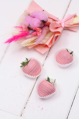 Pink Chocolate dipped Strawberries and Pink Dried Flowers Bouquet, on white wooden background.