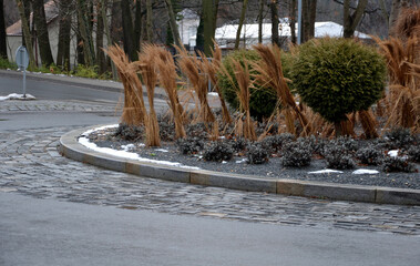 roundabout of paving gray granite cubes, transport hub, with flowers and grasses in the middle of...