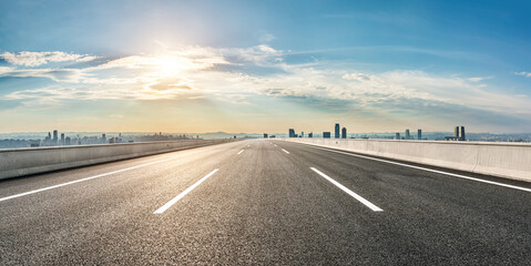 Fototapeta premium Straight asphalt road with modern city skyline and buildings