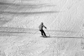 Skier descent on snowy ski slope. Black and white. High contrast.