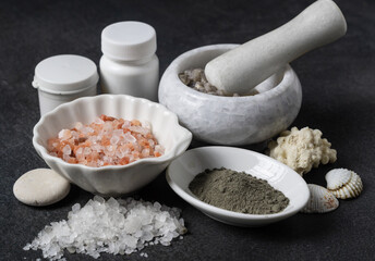 Crystals of white, gray, pink salt and sea mineral powder in bowls and in mortar