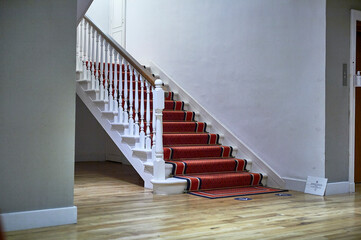 interior stairs with red carpet, balusters and wooden handrails