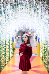 happy portrait young asian woman Santa costume and Christmas greeting picture parcel decoration on Christmas tree light Abstract circular bokeh background Decoration During Christmas and New Year.