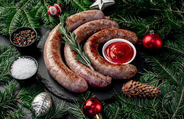 christmas grilled sausages with spruce and christmas toys on stone background