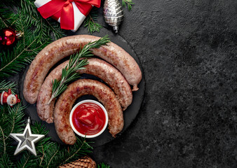 christmas grilled sausages with spruce and christmas toys on stone background with copy space for...