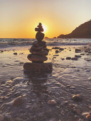 Fototapeta na wymiar Tower of pebble in the Kabak Valley beach and sunset.