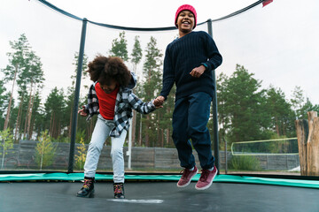 Black two boys making fun while jumping in bounce house