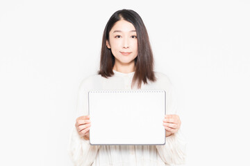 Naklejka premium 白い背景の前に立って、小さいスケッチブックを見せる主婦