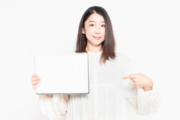 Naklejka premium 白い背景の前に立って、小さいスケッチブックを見せる主婦