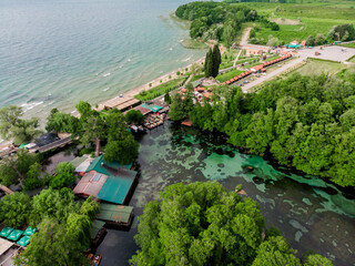 Drone shot of cafes and restaurants on the shores of Lake Ohrid. Drone view of green hilly mountains in Macedonia. The sandy beach of Lake Ohrid in northern Macedonia.