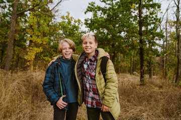 White two teenagers hugging and smiling during hiking in forest