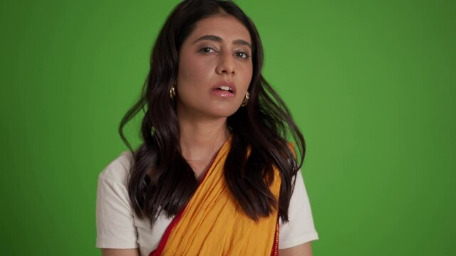 Handsome traditional Indian woman shrugging shoulders in the green studio
