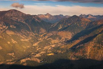 Naklejka premium Beautiful autumn in the Western Tatras. Yellow and orange grasses create an amazing atmosphere. The light of the setting sun illuminates the mountain ridges.