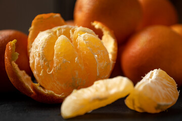 Half-peeled tangerine and peeled slices on table surface close up