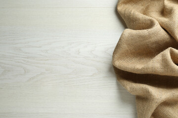 Natural burlap fabric on white wooden table, top view. Space for text