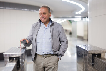 Middle aged man paying for entering subway with smartphone