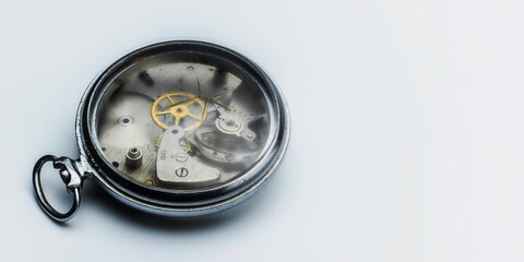 Old clock without a dial with cracked glass on a white gradient background. Gear wheels, pulleys. Macro photography. Full focus. The concept of the passing time.