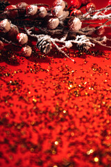 New Year, Xmas red background decorated with a decorative branch with red berries and golden confetti. Blurred background
