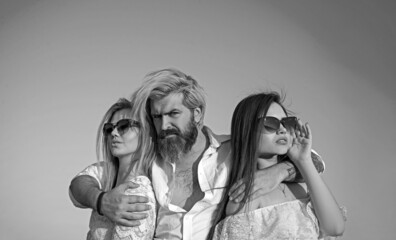 Young people friends of two pretty cute sexy girls or women and bearded man outdoors in park on...