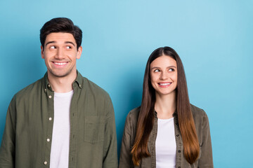 Photo of thoughtful dreamy young guy woman dressed khaki shirts smiling looking empty space isolated blue color background