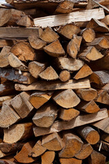 Firewood background. Photo is vertical. The firewood is stacked on top of each other. Wood heating concept. Raw materials for a boiler or furnace