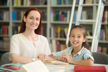 Woman and girl doing lessons looking at camera