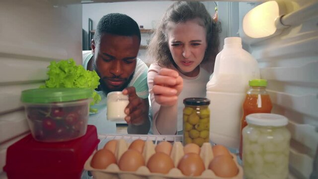 Multiracial couple open fridge with rotten food. Realtime