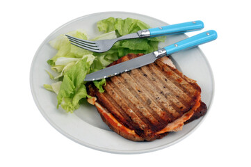 Croque-monsieur servi dans une assiette avec de la salade et des couverts en gros plan sur fond blanc