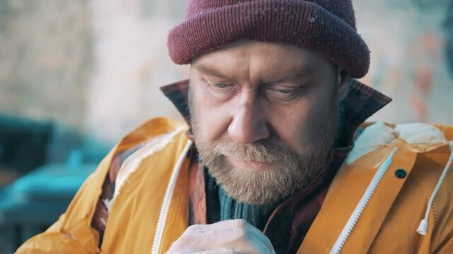 Close up of a tramp trying to warm up his hands