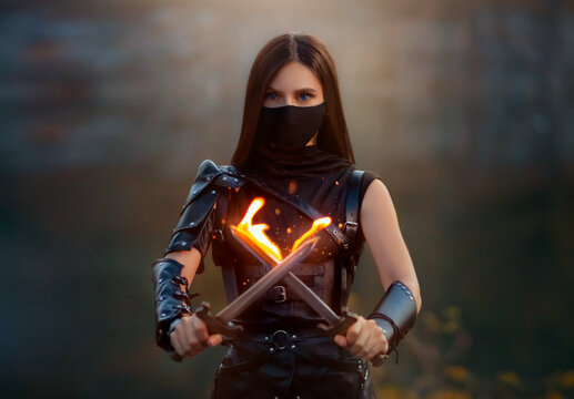 Fantasy fighting woman assassin holds in hands burning daggers. Red-haired girl warrior in black leather costume. ninja soldier with knives, fire magic. Strong face hidden behind mask, blue eyes.