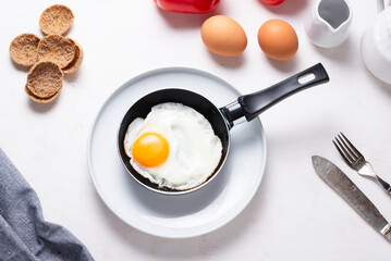 Scrambled, frying  eggs from one egg in a small pan on kitchen table