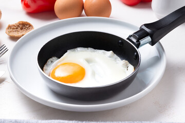 Scrambled, frying  eggs from one egg in a small pan on porcelain plate