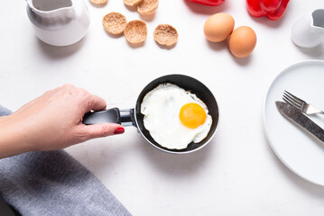 Woman hand holding small pan on kitchen table