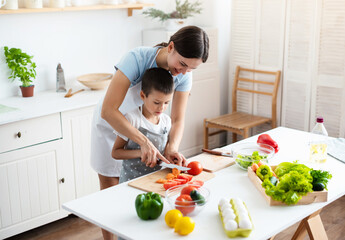 Cheerful mother helping her son to cook