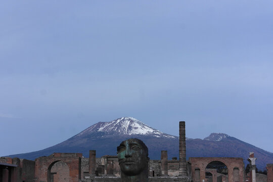 Fantastic view Mount volcano Vesuvius, snowy peak sky panorama. Excavations ancient city Pompeii. Conservation excavated incredible ruins. Preserved Roman heritage. Italy. Bronze art monument Mitoraj 