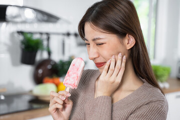 Asian Woman touching her chin feeling sensitive teeth when eating an ice cream. Have a gum and oral problem. - obrazy, fototapety, plakaty