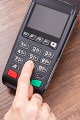 Hand of woman using credit card reader to enter PIN code. Cashless paying. Finance and banking