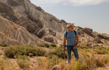 Naklejka na ściany i meble Portrait of adult man in cowboy hat in oasis of desert area. Shot in Almeria, Spain