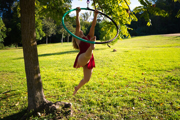 Blonde woman and young gymnast acrobat athlete performing aerial exercise on air ring outdoors in...