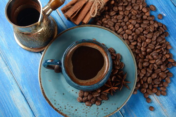 Coffee cup, cinnamon , сezve and beans on blue table