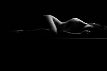 Sexy femme nue adulte isolée sur fond noir posant sensuelle dans la photographie de paysage corporel