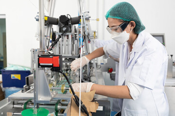factory worker using machine control panel and producing medical face masks in factory