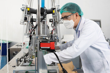 Naklejka premium factory worker using machine control panel and producing medical face masks in factory