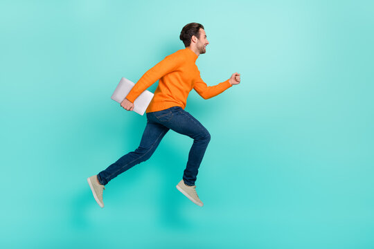 Full body profile side photo of young guy run rush fast hold laptop jumper isolated over teal color background